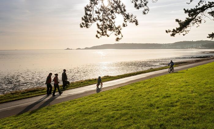 Cyclist and walkers on Coast Path at Blackpill at sunrise